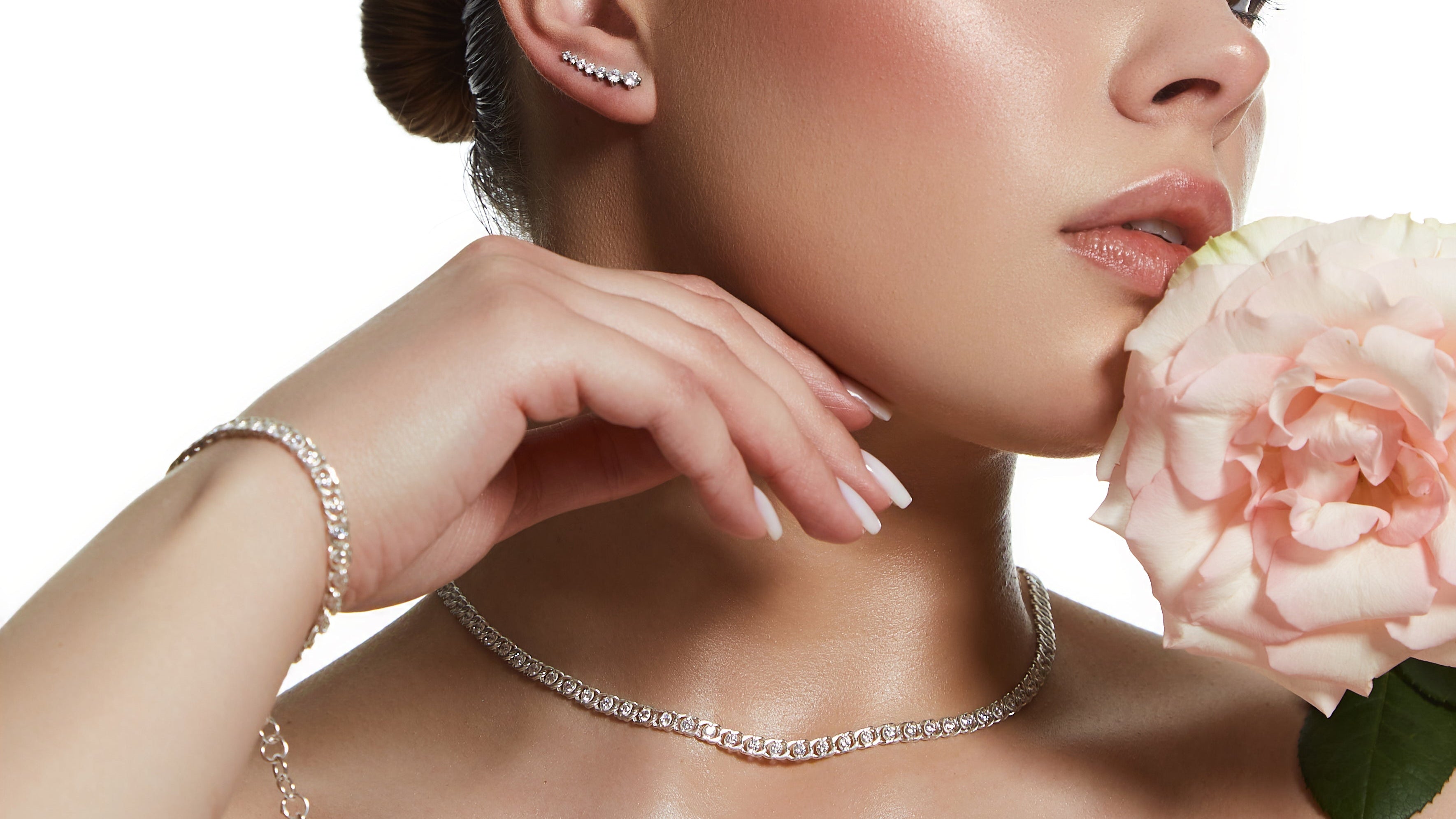 Woman wearing jewelry with a pink flower against a white background